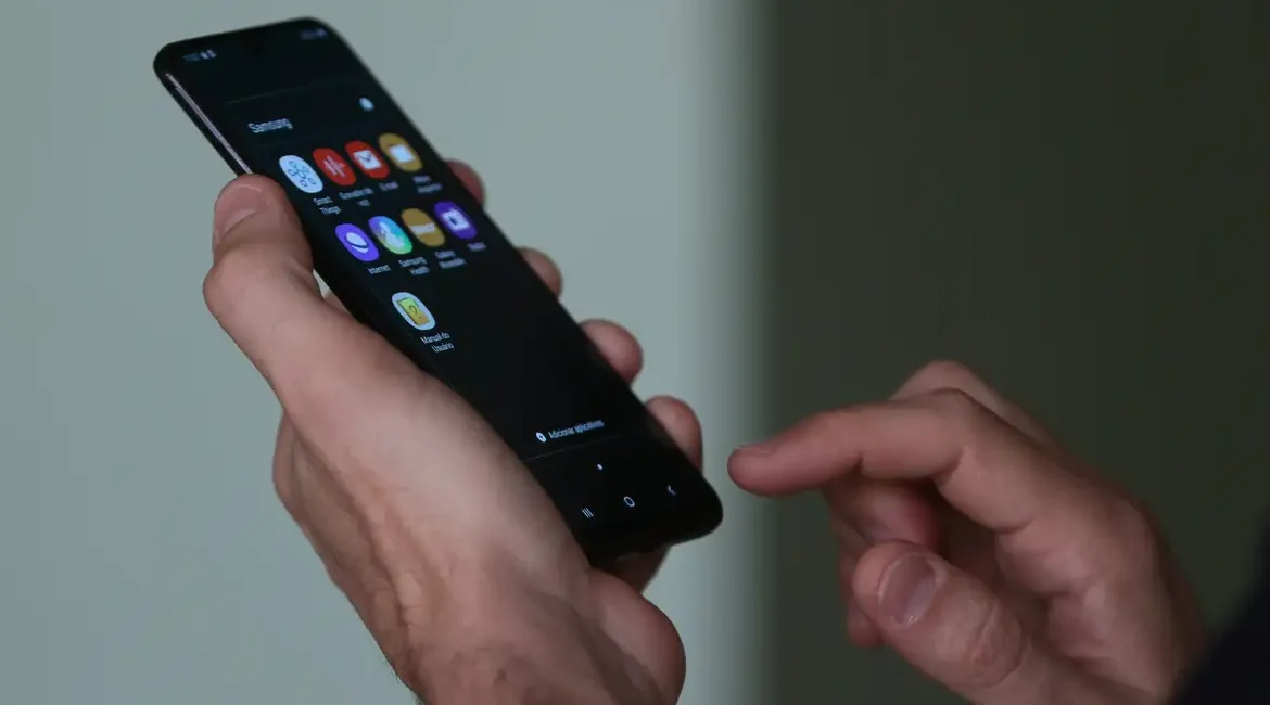 Aluno em sala de aula com smartphone, foco no uso de celular nas escolas.